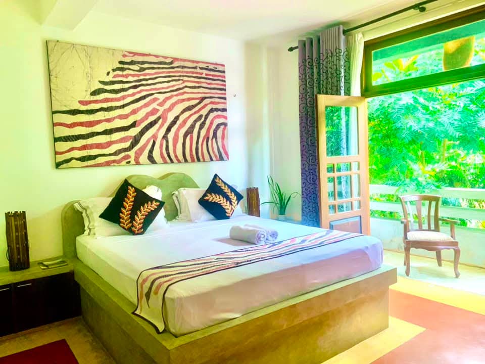 Deluxe Double Room at Gangula Villa — king bed with bold Kandyan red and black décor
